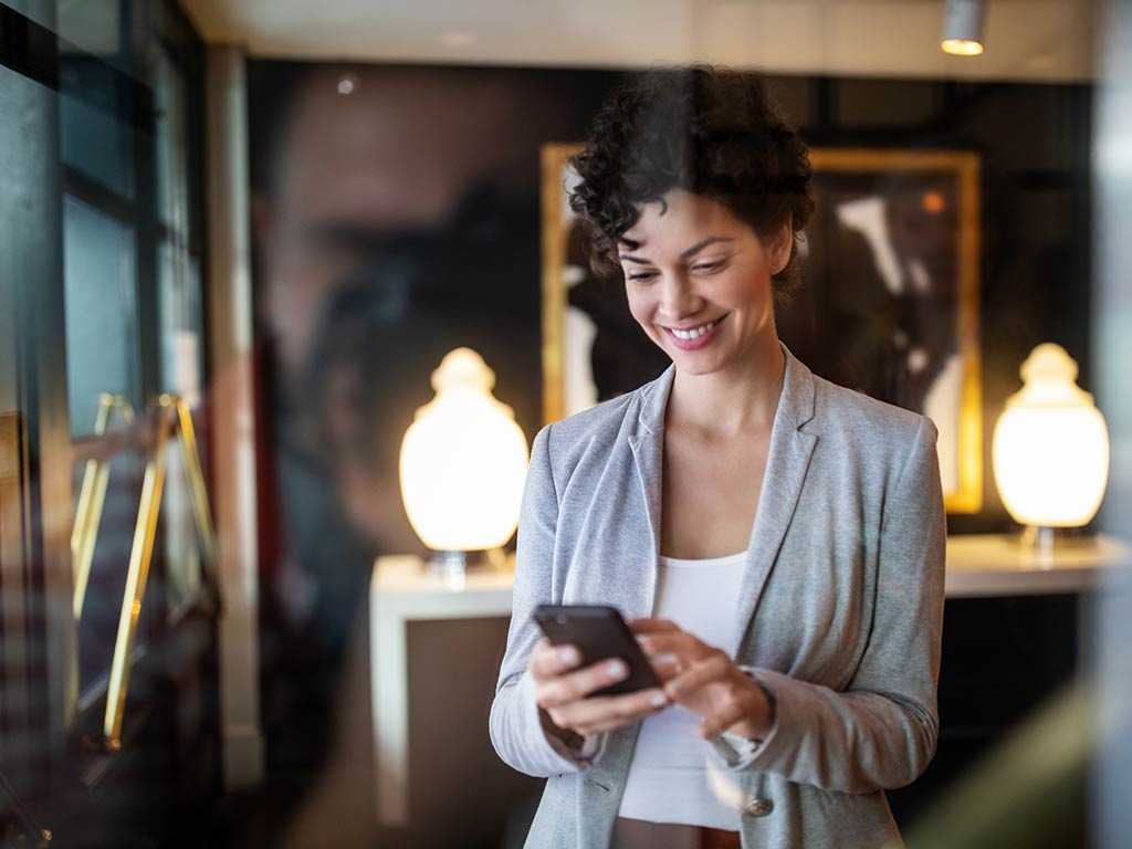 Woman standing in a lobby using her cell phone